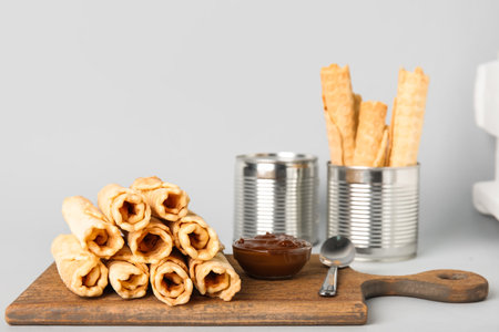 Board with stack of delicious wafer rolls on gray backgroundの写真素材
