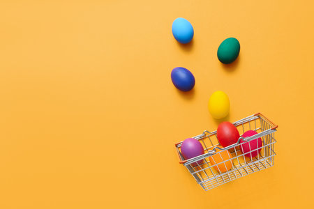 Shopping basket and Easter eggs on orange background