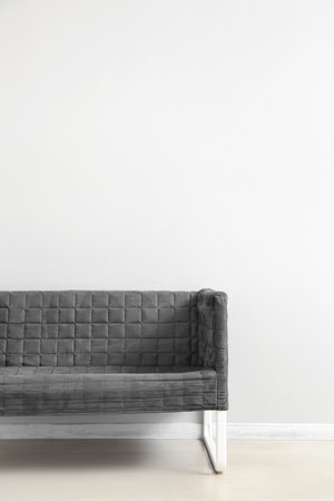 Stylish gray sofa near white wallの写真素材