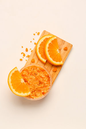 Wooden board with jar of natural body scrub, sea salt and orange slices on light backgroundの写真素材