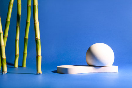 Green bamboo stems and plaster podiums on blue background