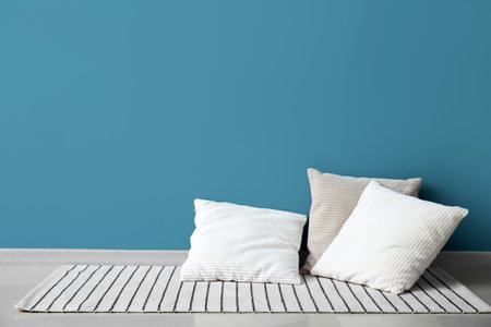 Stylish decorative pillows on rug near blue wallの写真素材
