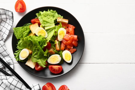 Plate of delicious salad with boiled eggs and salmon on white wooden backgroundの写真素材
