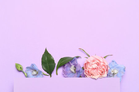 Beautiful composition with card and flowers on lilac backgroundの写真素材
