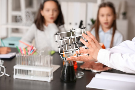Teacher with molecular model conducting lesson to little children in science classroom, closeupの写真素材