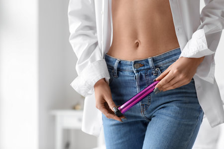 Young woman with vibrator in bedroom, closeupの写真素材