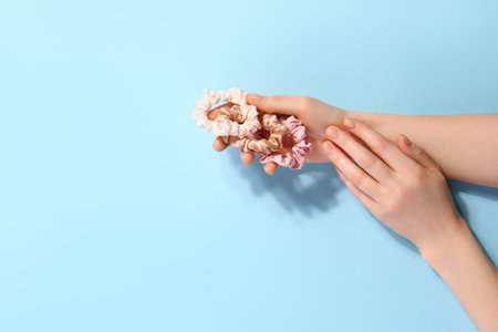 Female hands with stylish silk scrunchies on color backgroundの写真素材