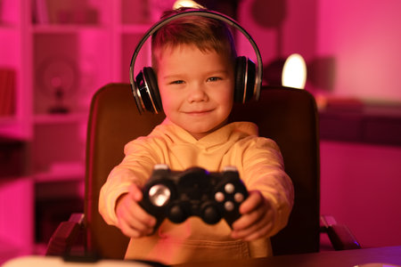 Cute little blogger in headphones with game pad at home