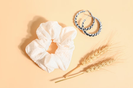 Stylish scrunchy, earrings and wheat spikelets on color backgroundの写真素材