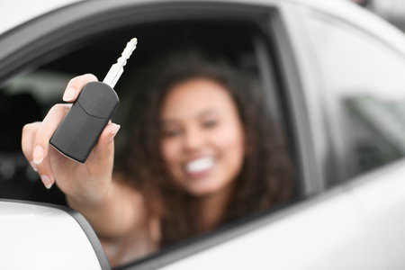 Young African-American woman with key sitting in new carの写真素材