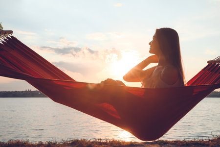 Silhouette of young woman relaxing in hammock outdoorsの写真素材