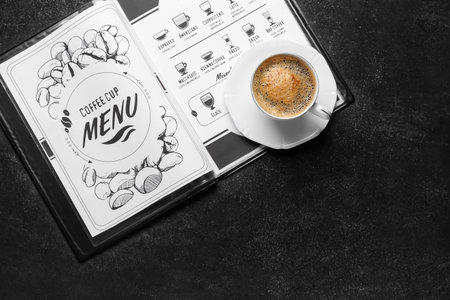 Cup of hot coffee and menu on table in cafeの写真素材