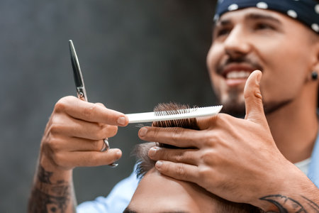 Professional hairdresser working with client in barbershopの写真素材