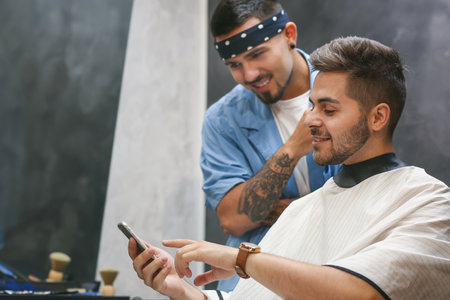 Professional hairdresser working with client in barbershopの写真素材