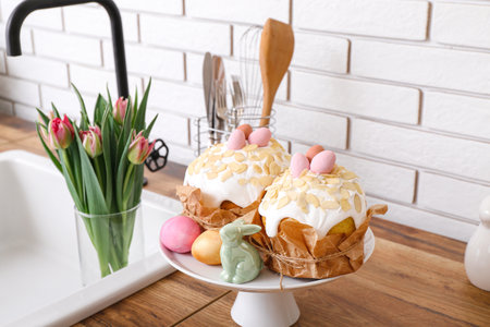 Dessert stand with Easter cakes, painted eggs and bunny on kitchen counterの写真素材