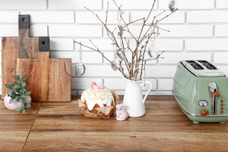 Vase of willow branches, Easter cake with painted eggs and bunny on kitchen counter