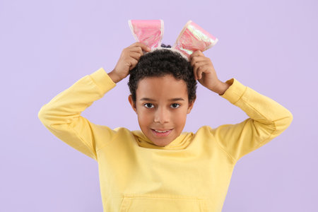 African-American little boy in bunny ears on lilac background, closeup