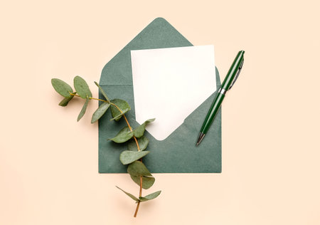 Envelope with blank card, pen and eucalyptus branch on color backgroundの写真素材