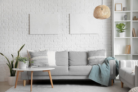 Gray sofas with cushions and houseplant on table in interior of living room
