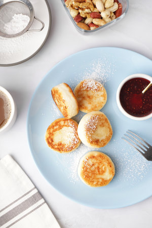 Plate with tasty cottage cheese pancakes and strawberry jam on light background, closeupの写真素材