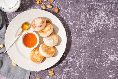 Plate with tasty cottage cheese pancakes and jam on grunge background