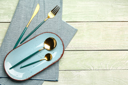 Blue tablecloth with plate and set of cutlery on green wooden backgroundの写真素材