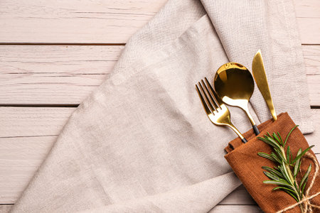 Napkin with set of cutlery and gray tablecloth on white wooden backgroundの写真素材