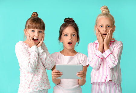 Cute little girls with tablet computer on color backgroundの写真素材