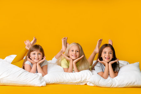 Cute little girls with pillows on color backgroundの写真素材