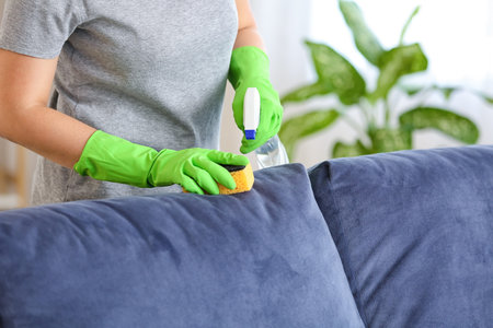 Woman removing dirt from sofa at home
