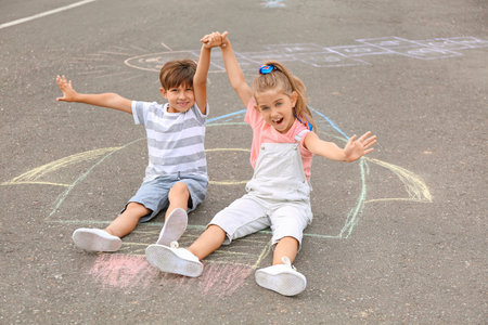 Little children sitting on chalk drawing of rocket outdoorsの写真素材