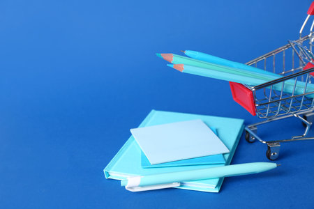 Shopping cart with stationery on blue backgroundの写真素材