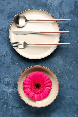 Table setting with beautiful gerbera flower on blue grunge backgroundの写真素材