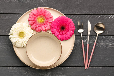 Table setting with beautiful gerbera flowers on black wooden backgroundの写真素材