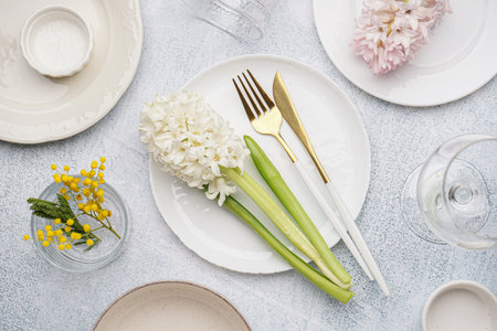 Composition with clean dishes, cutlery and beautiful flowers on gray grunge background