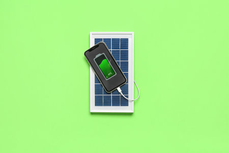 Portable solar panel charging mobile phone on green backgroundの写真素材