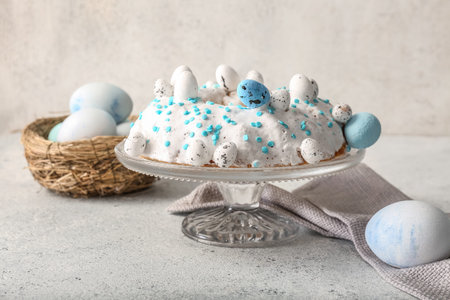 Dessert stand with tasty Easter cake and painted eggs on gray table