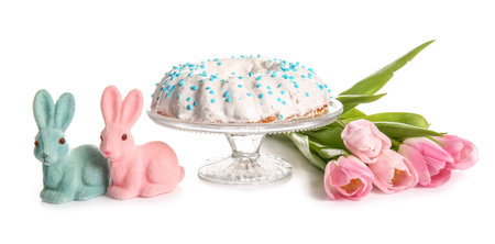 Dessert stand with tasty Easter cake, toy bunnies and tulip flowers isolated on white background