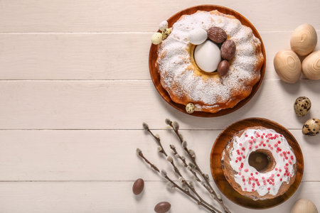 Composition with tasty Easter cakes, eggs and willow branches on white wooden background