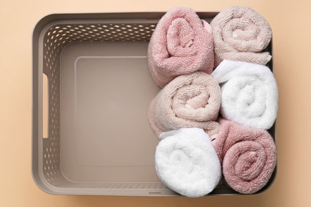 Basket with rolled soft towels on beige backgroundの写真素材