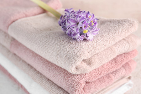 Stack of folded soft towels and hyacinth flower on tableの写真素材