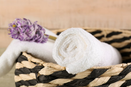 Basket with rolled soft towels and hyacinth flower on green wooden tableの写真素材