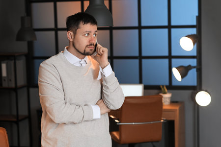 Male accountant talking by mobile phone in office at night