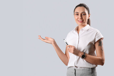 Female business consultant with marker showing something on gray backgroundの写真素材