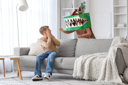 Scared little boy and his sister in cardboard dinosaur costume at homeの写真素材