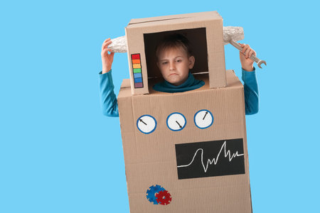 Little boy in cardboard robot costume on blue background