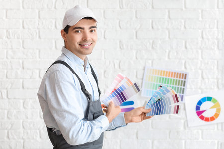 Male painter with palette colors near white brick wallの写真素材
