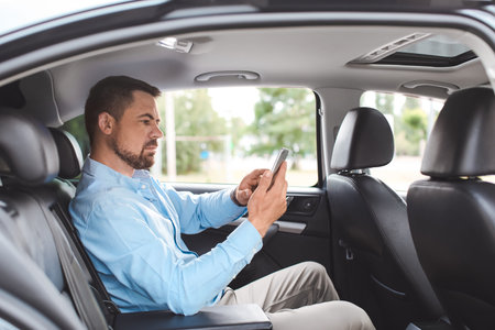 Handsome man with mobile phone in modern car