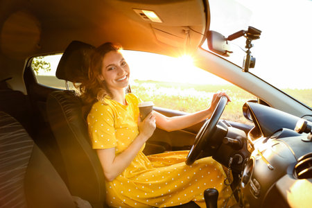 young woman drinking coffee in carの写真素材