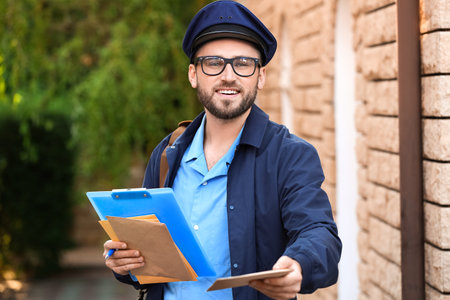 Handsome young postman with letters outdoorsの写真素材